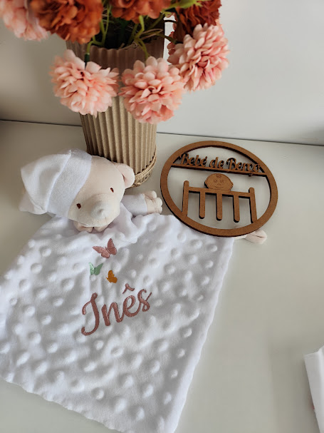 Boneco de peluche com tecido branco bordado com nome e sinal de madeira com texto