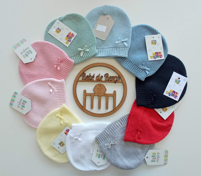 Toucas de malha coloridas com fitas e etiqueta, dispostas em círculo com placa de madeira ao centro