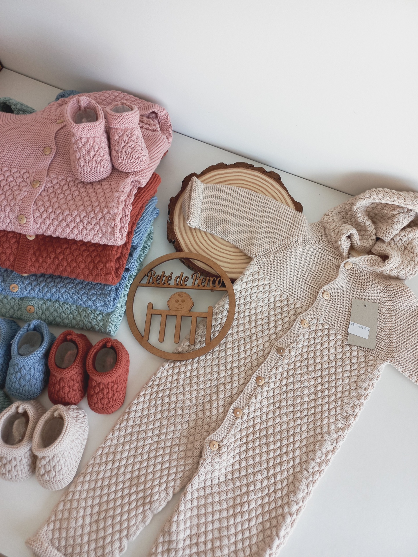 Roupas de bebé em tricot com padrão texturizado e várias cores com sapatinhos correspondentes.