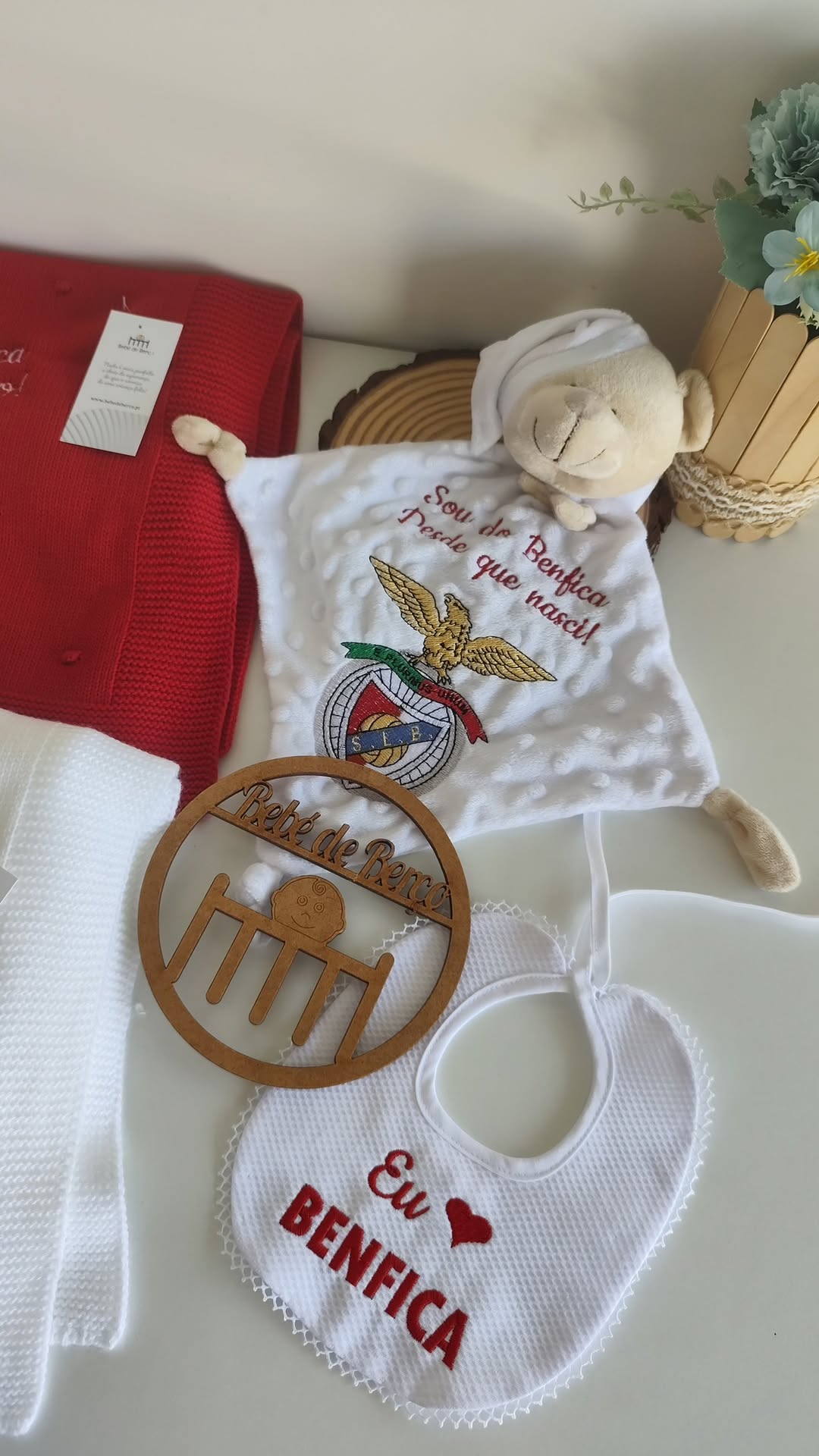 Artigos para bebé com tema Benfica, toalha, manta, babete e ornamento de madeira.