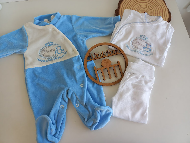 Conjunto de roupa de bebé azul e branco com bordados e elemento decorativo em madeira