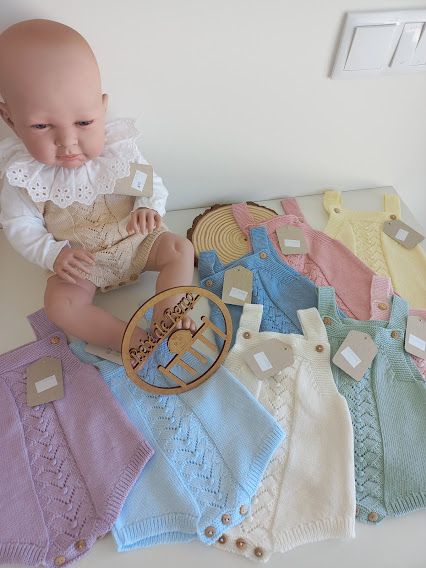 Boneco bebé com fatos de malha coloridos e um cesto de palha