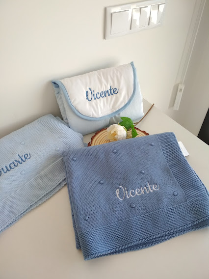 Peças têxteis azul e branca com nomes bordados sobre uma superfície branca