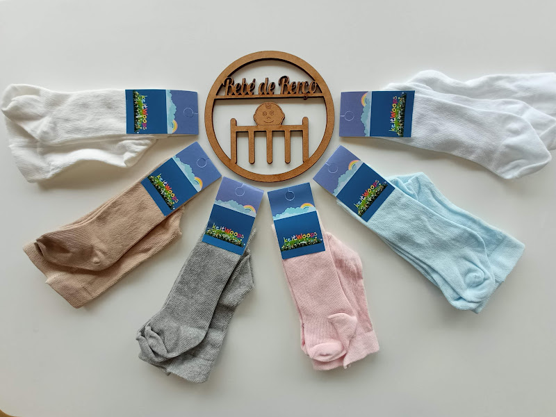 Seis pares de meias coloridas com etiquetas azuis dispostos em semicírculo junto a objeto de madeira redondo