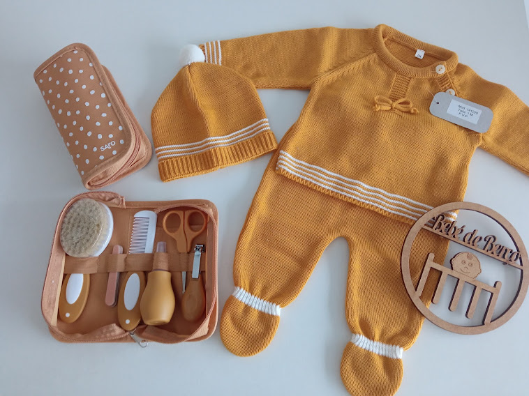 Conjunto de roupa e acessórios de bebé, macacão amarelo, gorro, necessaire com utensílios e placa de madeira
