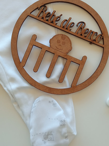 Meia branca com padrão cinza claro e placa redonda de madeira com texto Bebé de Benca e figura de bebé