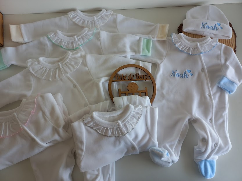 Conjunto de roupa de bebé branco com detalhes em azul, verde, rosa e bege e bordado com o nome Noah.