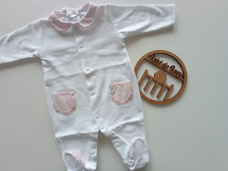 Pijama branco de bebé com detalhes cor-de-rosa e placa de madeira ao lado