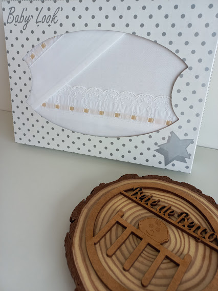 Roupinha de bebé branca com renda em embalagem com padrão de bolinhas cinzentas