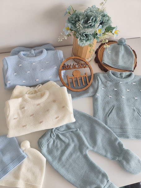 Conjunto de roupa de bebé em malha azul, branco e cinzento com flores artificiais e ornamento de madeira