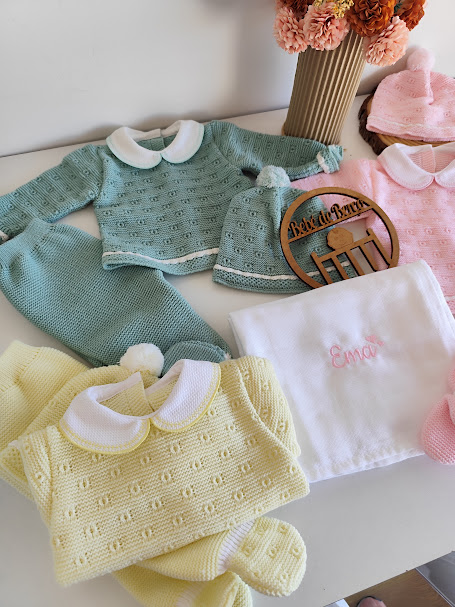 Conjunto de roupa de bebé em malha com diferentes peças coloridas e fralda bordada