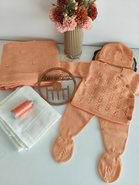 Conjunto de roupa de bebé em malha coral com camisola, calças fechadas, gorro, cobertor e acessórios em fundo branco