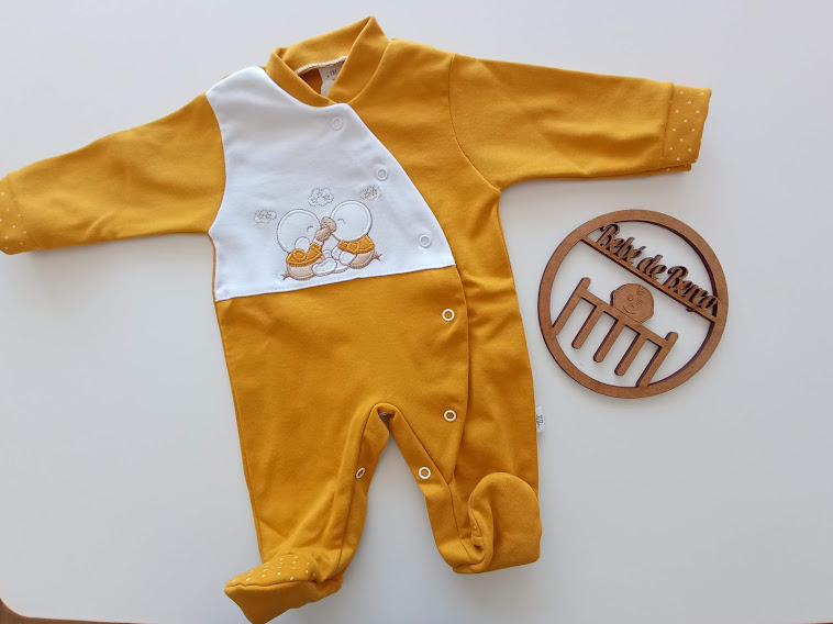 Macacão de bebé amarelo com estampa de patinhos e placa de madeira com berço e texto Katia Borges