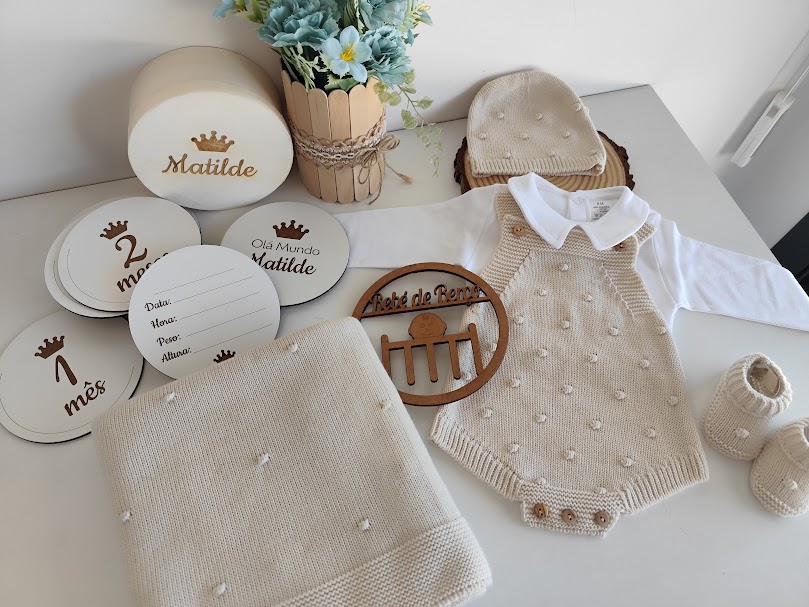 Conjunto de bebé bege em malha com body, gorro, sapatinhos, manta e discos redondos com texto Matilde e 1 mês