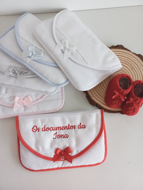 Bolsas de tecido branco com laços coloridos e bolsa com bordado vermelho 'Os documentos da Íona' com sapatinhos vermelhos