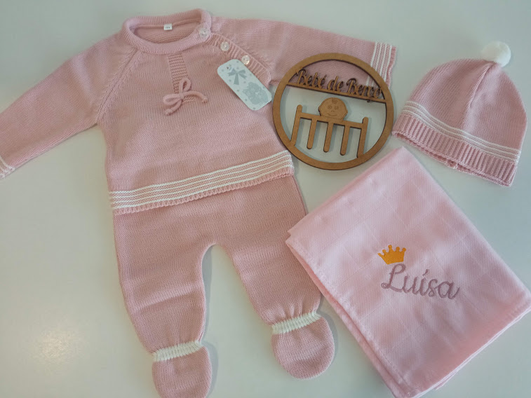 Conjunto de roupa de bebé rosa com macacão, gorro, manta bordada e enfeite de madeira