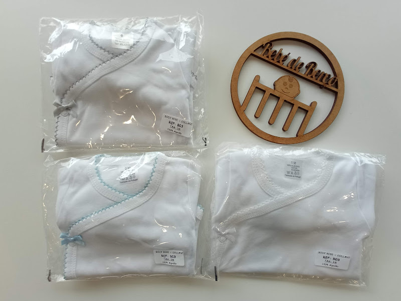 Três bodies de bebé brancos embalados com costuras coloridas e ornamento de madeira com texto