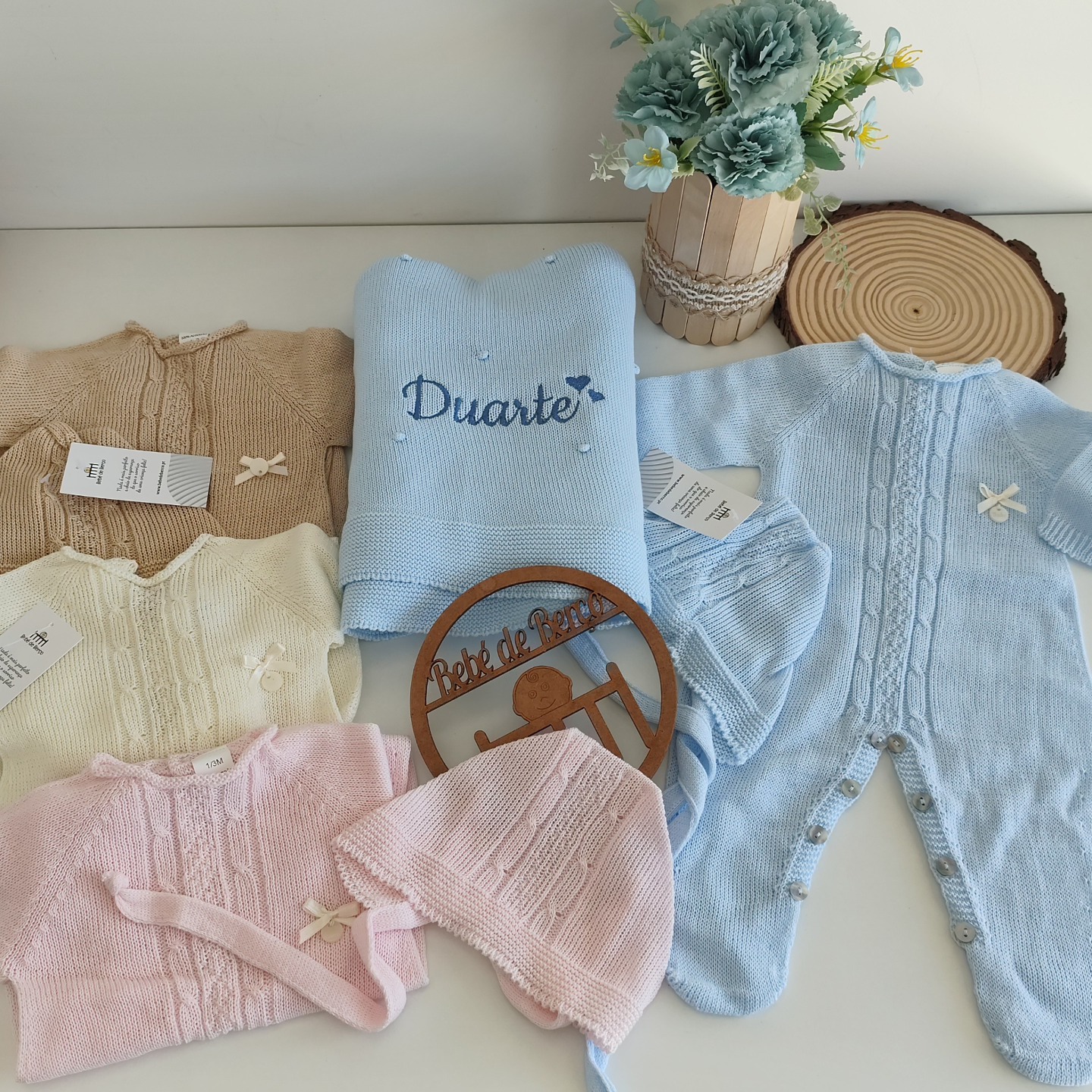 Roupas de bebé em malha de várias cores com decoração e nome bordado.