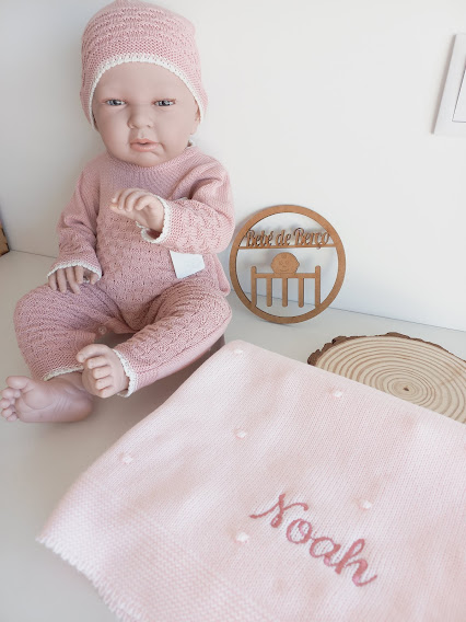 Boneco de bebé com roupa e gorro rosa e manta bordada com o nome Noah