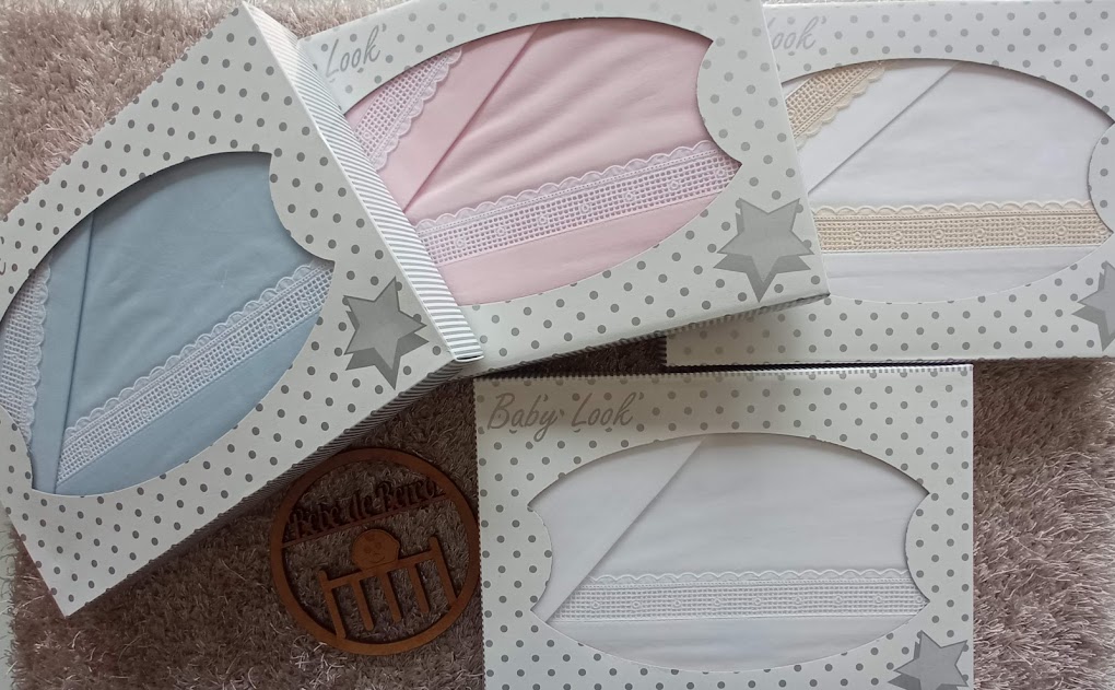 Conjunto de quatro fraldas para bebé em caixas coloridas em azul, rosa, bege e branco com detalhes de renda.