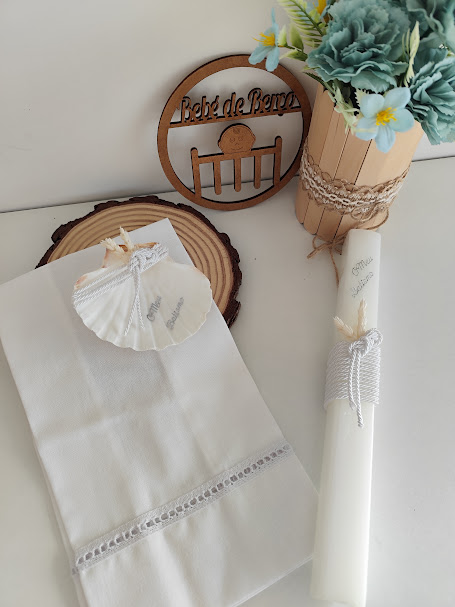 Cachecol, anel em concha, vela branca com texto e vaso decorativo com flores artificiais