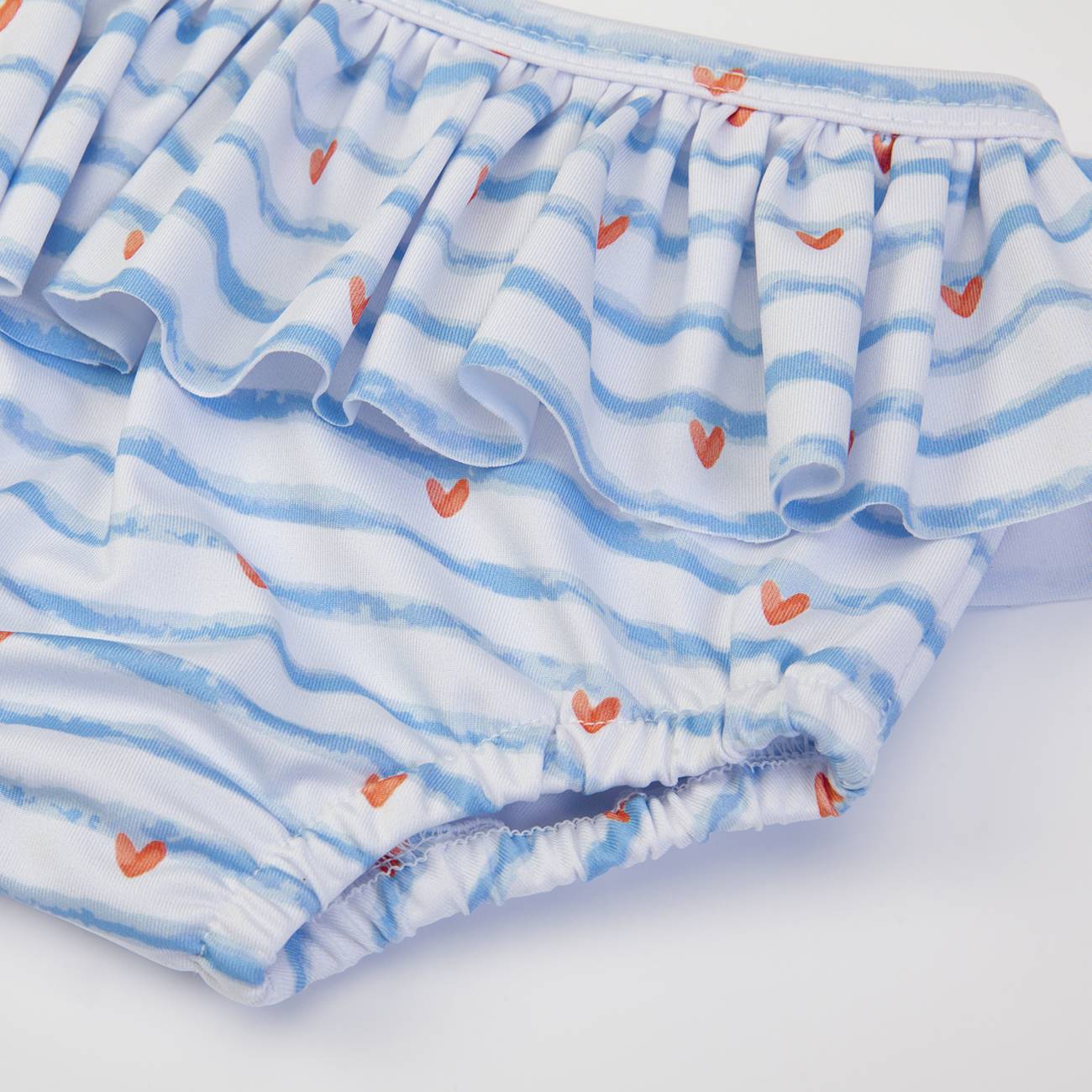 Roupa infantil com riscas azuis e corações laranja com folho.