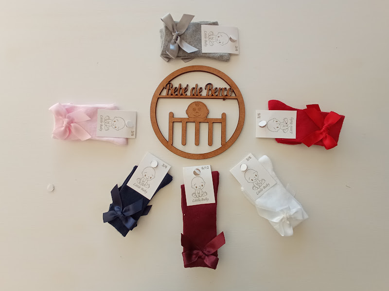 Pares de meias de bebé coloridas com laços e letreiro redondo de madeira 'Pé de Peque' ao centro