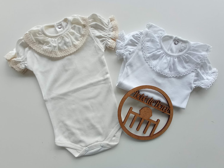 Dois bodies de bebé com gola e mangas em renda, um branco e outro creme, sobre fundo branco com logótipo de madeira