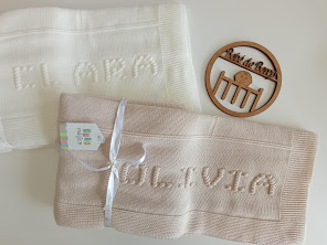 Tecidos bordados com nomes 'ELENA' e 'OLIVIA', etiqueta colorida e objeto de madeira gravado ao lado.