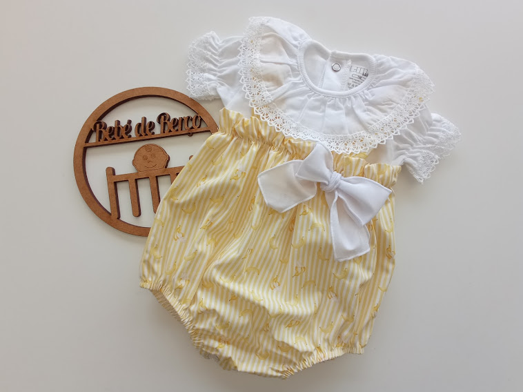 Body de bebé branco com gola rendada e parte inferior amarela com laço branco