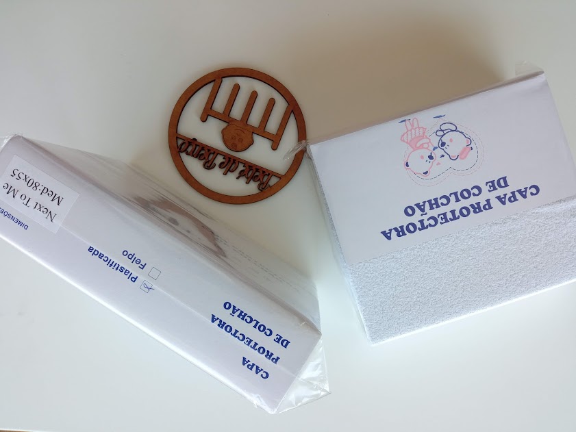 Duas capas protetoras de colchão brancas, uma embalada e outra com desenho de ursinho