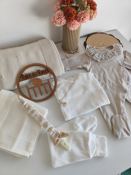 Conjunto de roupa e acessórios para bebé neutros com flores e decoração em madeira