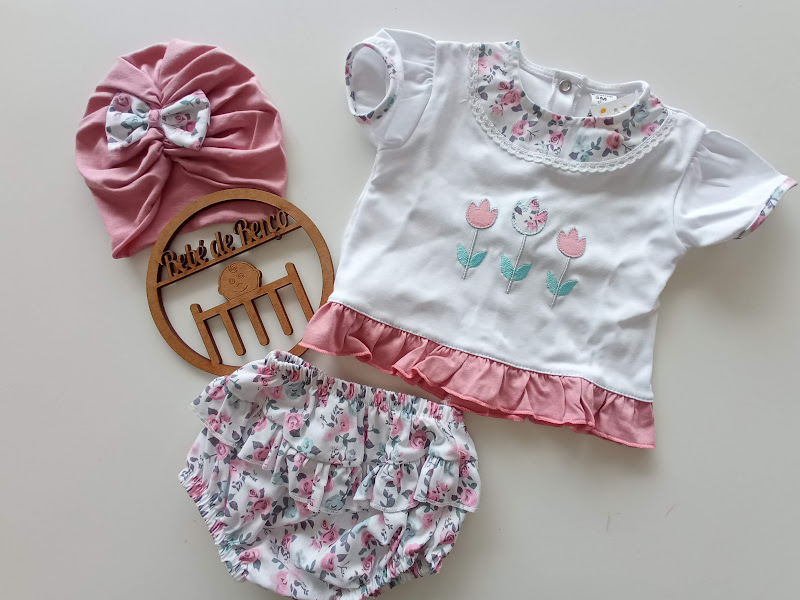 Conjunto de bebé com camisola branca e rosa bordada, tapa-fraldas floral e gorro rosa com laço floral