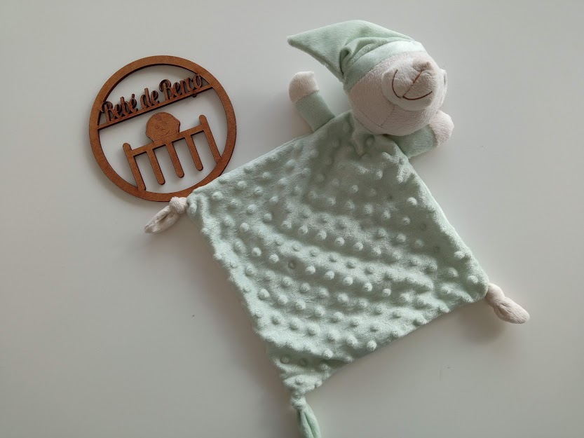 Brinquedo de peluche verde menta com cabeça de animal e placa de madeira com texto ELITE DA MESA