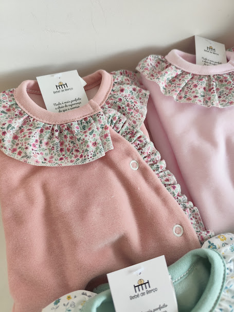 Três bodies de bebé com folhos e padrão floral, cores rosa claro, rosa escuro e verde-água