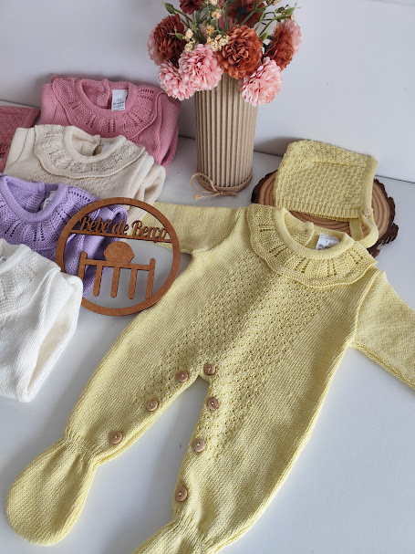 Macacão de bebé amarelo claro em malha com botões e gola bordada com flores e outras peças em fundo branco