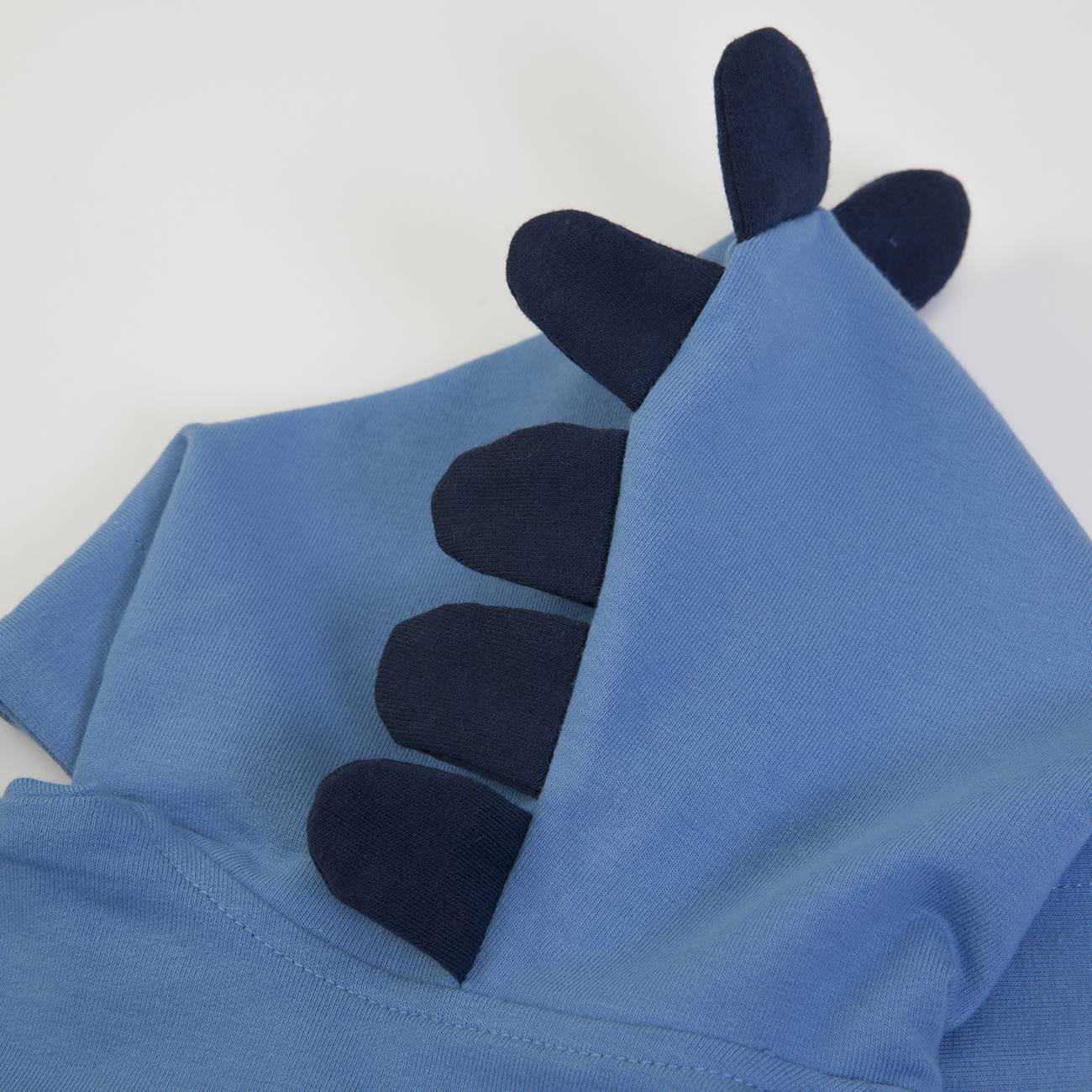 Peça de roupa azul com capuz e detalhes pretos que parecem cristas