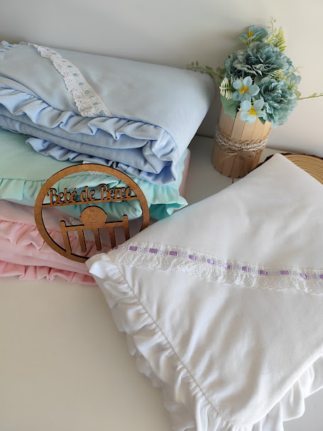 Mantinhas de bebé em algodão e renda com cores suaves e arranjo floral decorativo