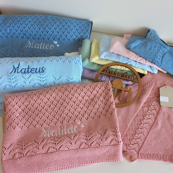 Mantas e roupa de bebé em malha com nomes bordados e cabide de madeira