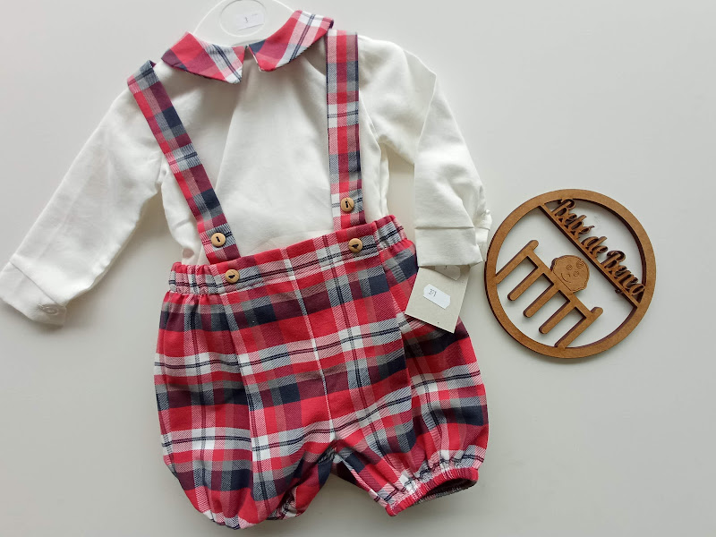 Conjunto de bebé com camisa branca e calções xadrez com alças sobre superfície branca
