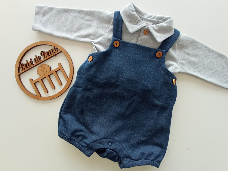 Conjunto de roupa de bebé com camisola cinzenta e macacão azul escuro, e placa redonda decorativa em madeira