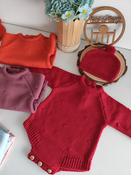 Roupas de bebé em malha colorida com decoração e placa de madeira