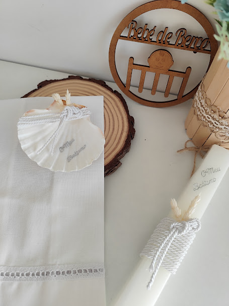 Conjunto de batizado com toalha branca, concha, vela decorada e peça decorativa de madeira