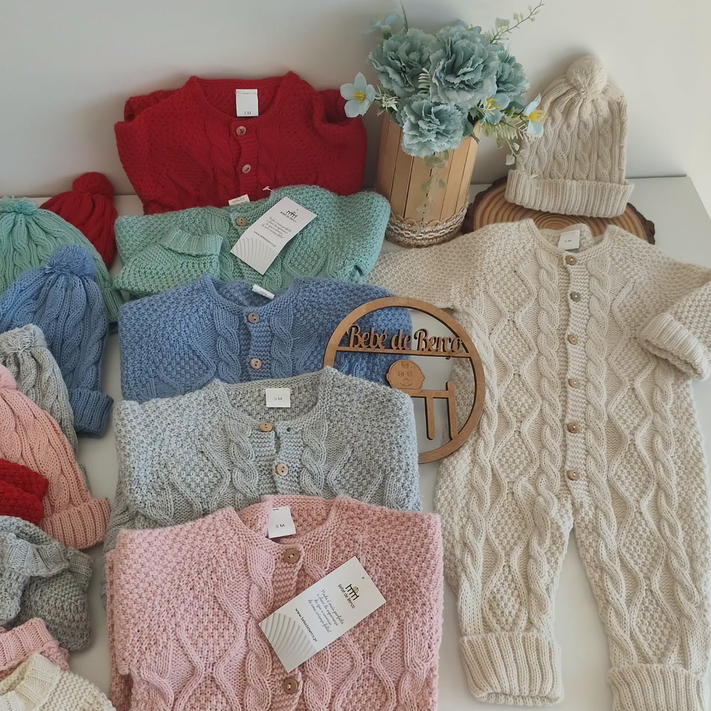 Roupa de bebé em malha colorida com casacos, gorros e macacão creme