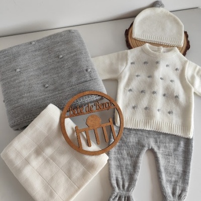 Conjunto de roupa de bebé em cinzento e branco com gorro, casaco, calças, mantas e placa de madeira