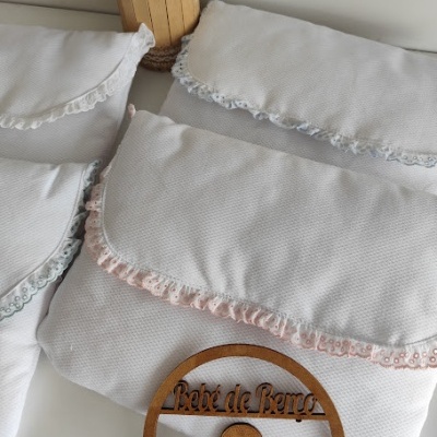 Três almofadas brancas com bordas em renda de cores diferentes e enfeite de madeira Bebé de Berço