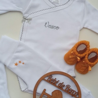 Conjunto de roupa de bebé branco com bordados e botins laranja