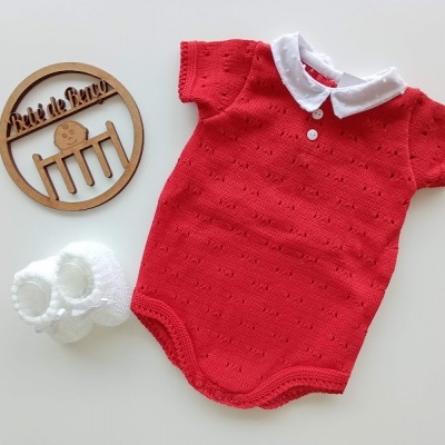Body de bebé vermelho com gola branca e sapatinhos brancos em fundo branco