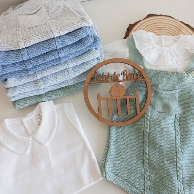 Conjunto de roupa de bebé com body verde, camisola branca e casacos de malha azul e verde empilhados