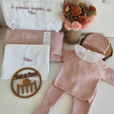 Conjunto de roupa de bebé rosa claro em malha com bordados, arranjo de flores e fralda bordada